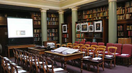 The Upper Library arranged with seating arranged in Parliamentary Style and reproduction paintings from the period on the bookshelves